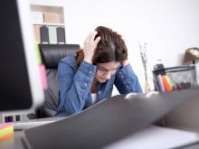A woman with head in hands, frustrated because the website is down!